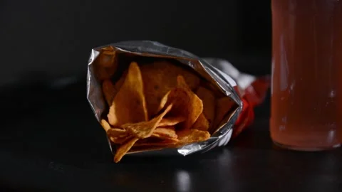 Close up of an open bag of tortilla chips and a glass bottle placed nearby. 库存影片 336483062