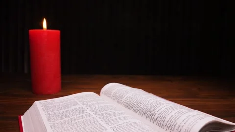 Close-up of open Bible and a red burning candle in rotation. Easter. Stock Footage 304106126