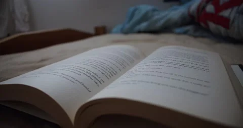 Close-up of Open Book on Bed Stock Footage 141553944
