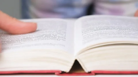 Close-up of an open book with pages being flipped by hand. Reading, studying, or Stock Footage 318802776
