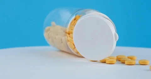 Close-up open bottle transparent orange tablets rotates blue background Stock-Footage 126339212