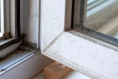 Close up of an open, dirty plastic window frame with wood block, showing sign Stock Photos