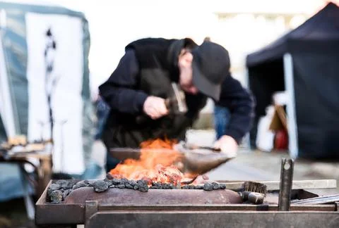 Close up of open fire and blacksmith working in the background. Ironwork conc Foto stock