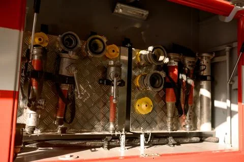 Close-up of open fire engine compartment with hoses and coupling heads. Stock Photos