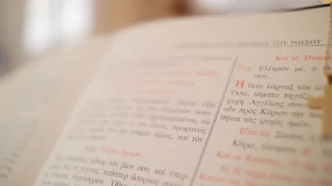 Close up of an open Greek bible with a cross necklace draped over it Stock Footage