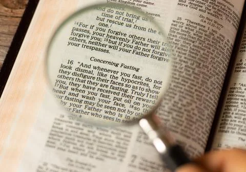 Close up open Holy Bible Book with magnifying glass on fasting passages Stock Photos