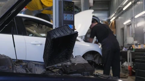 Close-up of the open hood of a car at a service station.Replacing the air filter Stock Footage 297844198