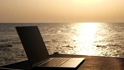 Close-up, an open laptop lies on the table in the sunlight, against the Stock Footage 136893499
