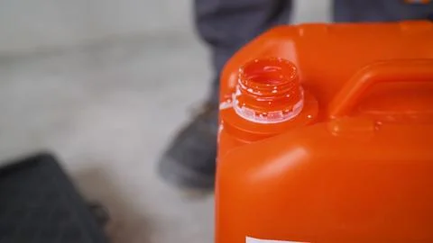 Close up on open orange plastic canister with white liquid spilled on neck,.. Stock Photos