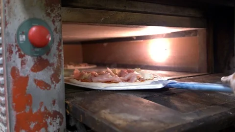 Close-up of an open oven in which the cook puts cooked pizza for frying. Video stock 104866550