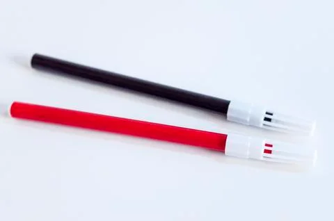 Close-up open shoot of red and black magic marker on white surface Stock Photos