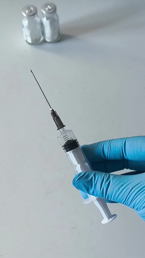 Close-up of an open syringe with a needle in the doctors hand. Concept of Stock Footage 322217589