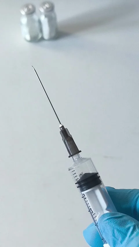 Close-up of an open syringe with a needle in the doctors hand. Concept of Stock Footage 322217646