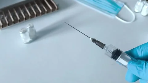 Close-up of an open syringe with a needle in the doctors hand. Concept of Stock Footage 322218470