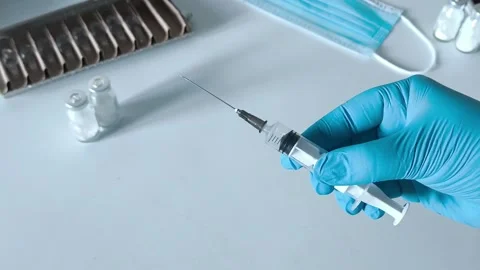 Close-up of an open syringe with a needle in the doctors hand. Concept of Stock Footage 322218563