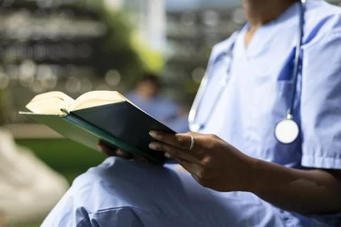 Close up of open textbook and hands as medical student reads on bench Stock Photos