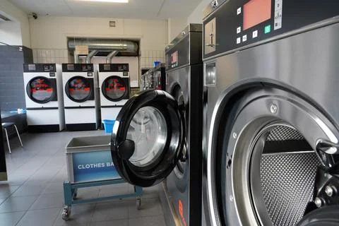 Close up of open wash machine in a public laundry for coin wash. Stock Photos