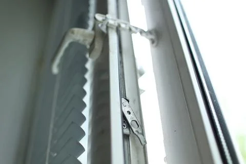Close up of an open white plastic window secured by a metallic comb restrictor Stock Photos