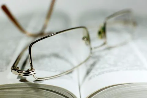 Close up opened book page and reading eyeglasses Stock Photos
