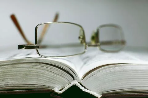 Close up opened book page and reading eyeglasses Stock Photos