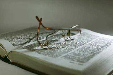 Close up opened book page and reading eyeglasses Stock Photos