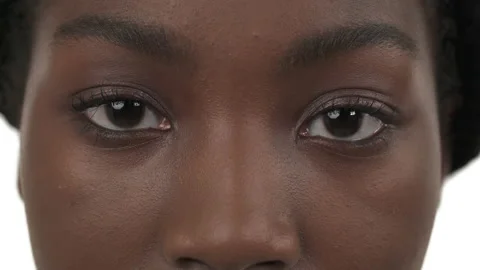 Close-up of opened brown eyes of young black woman. Moving eyes to left and Video stock 135897218