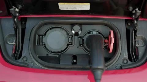 CLOSE UP: Opening charging port and plugging electric cable in, recharging the Stock-Footage 336585578