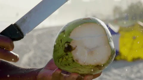 Close-up of opening coconut with machete at beach, slow motion. Stock Footage 149829695