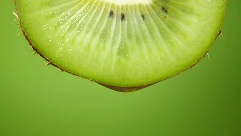 Close up or macro of a slice of kiwi, a drop of water falls in slow motion. Stock Footage 101474186