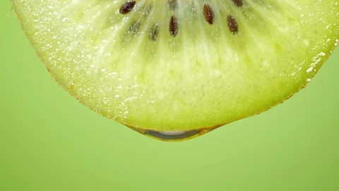 Close up or macro of a slice of kiwi, a drop of water falls in slow motion. Stock Footage 101474259