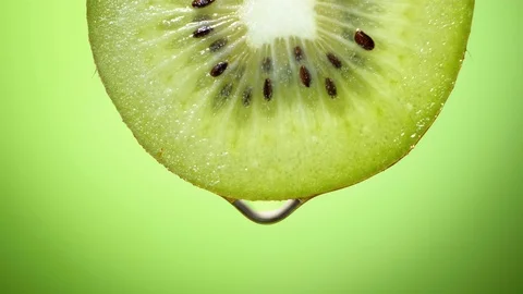 Close up or macro of a slice of kiwi, a drop of water falls in slow motion. Stock Footage 101474654