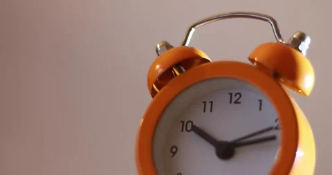 Close up a orange alarm clock with a white face showing the time of 10:10 on  库存影片 300364251
