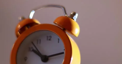 Close up a orange alarm clock with a white face showing the time of 10:10 on  Stock-Footage 300364501