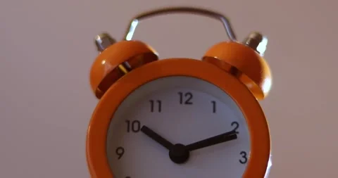 Close up a orange alarm clock with a white face showing the time of 10:10 on  Stock-Footage 300364522