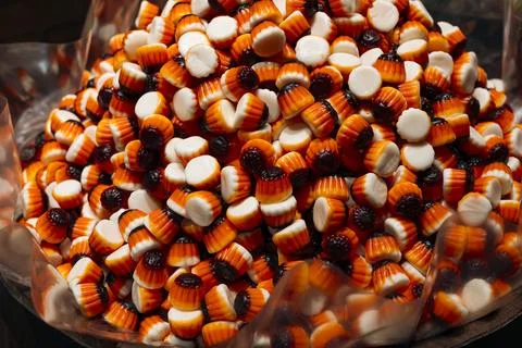 Close up of orange and black candy in container in candy shop. Stock Photos