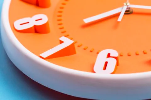 Close up Orange clock on blue background ,concept of Start the morning Stock Photos