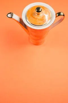 A close up of an orange covered ceramic teapot on an orange isolated backgrou Fotos de archivo