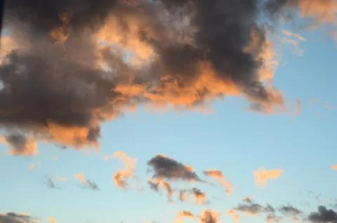 Close-up of orange dark  clouds at sunset against blue sky . Stock Photos