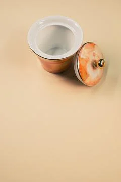 A close up of an orange empty cup next to a cover on an orange isolated backg Fotos de archivo