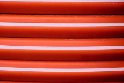Close-up of an orange flexible plastic pipe used in public works. Stock Photos