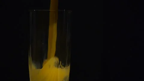 Close-up. Orange juice being poured in a tall glass on a black background Stock-Footage 106204906