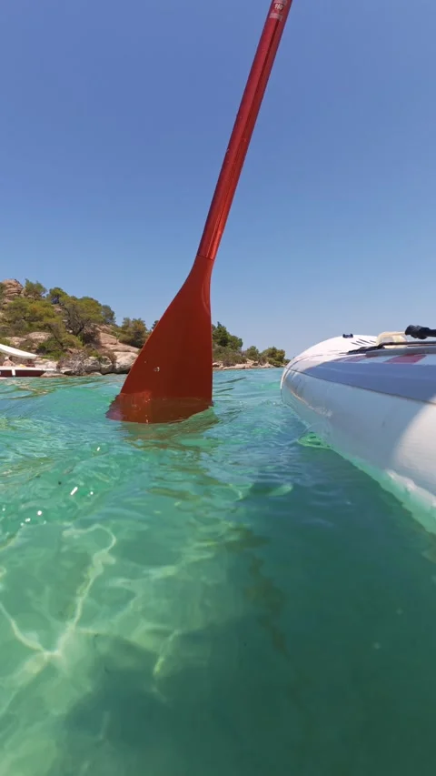 Close-up of orange paddle and paddleboard on crystal-clear turquoise water near Stock Footage 313802513