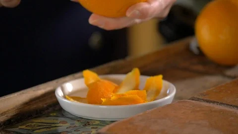A close-up of orange peels dropping onto a plate after peeling it. Stock Footage 113693347