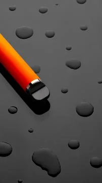 Close-up of an orange pen on a black surface with water droplets at midday Stock Photos