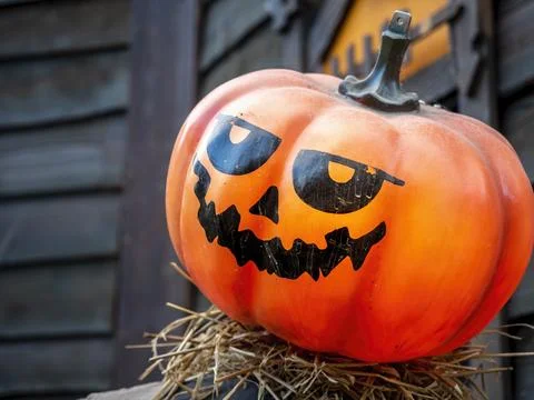 Close-up of an orange plastic Jack-O-Lantern on a straw platform Stock Photos
