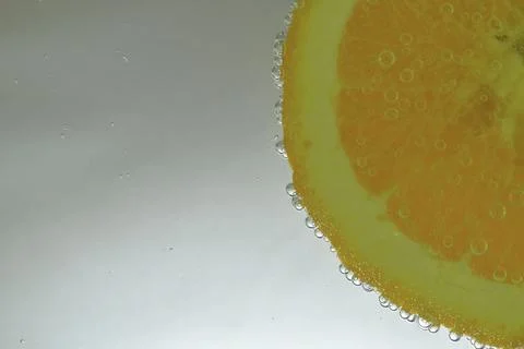 Close-up of an orange slice in liquid with bubbles. Slice of ripe orange frui Фото
