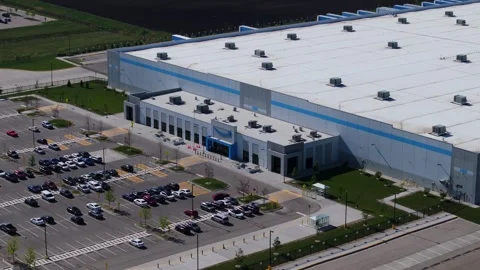 Close orbiting drone shot above an Amazon fulfillment center entrance revealing Stock Footage 338158124
