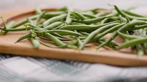 Close up of organic green beans scattered on a kitchen wooden board Stock Footage 343555667