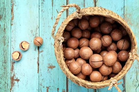 Close up of Organic Macadamia nuts in basket on a light blue table.  Stock Photos