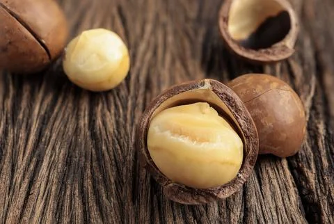 Close up of Organic Macadamia nuts on old wooden rustic table.  Stock Photos